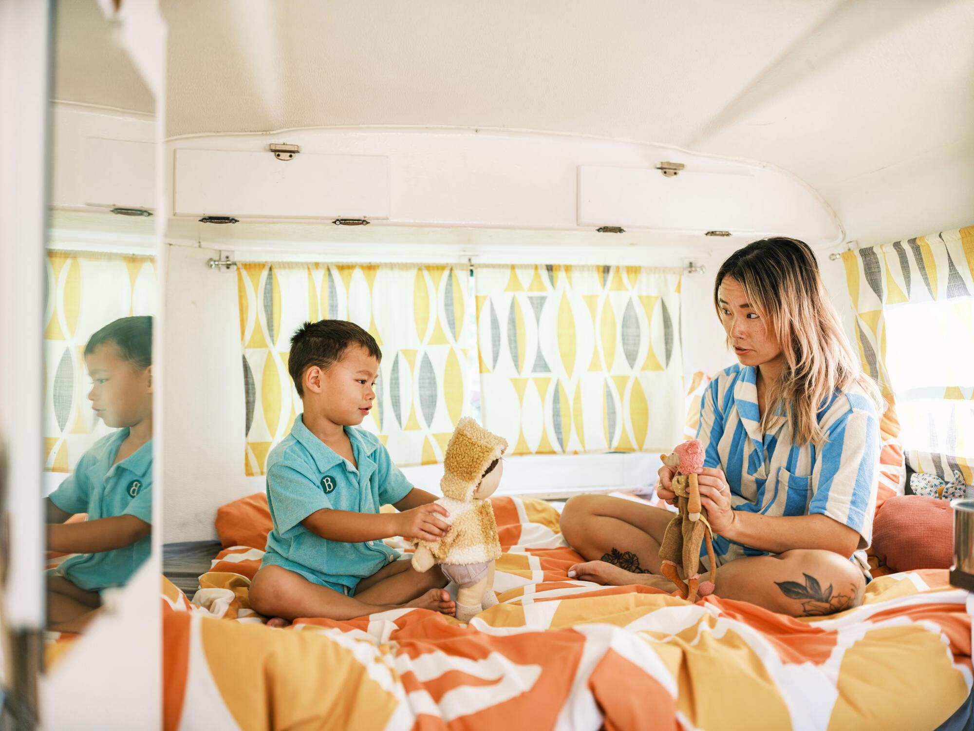 A mother and son playing with toys inside a trailer